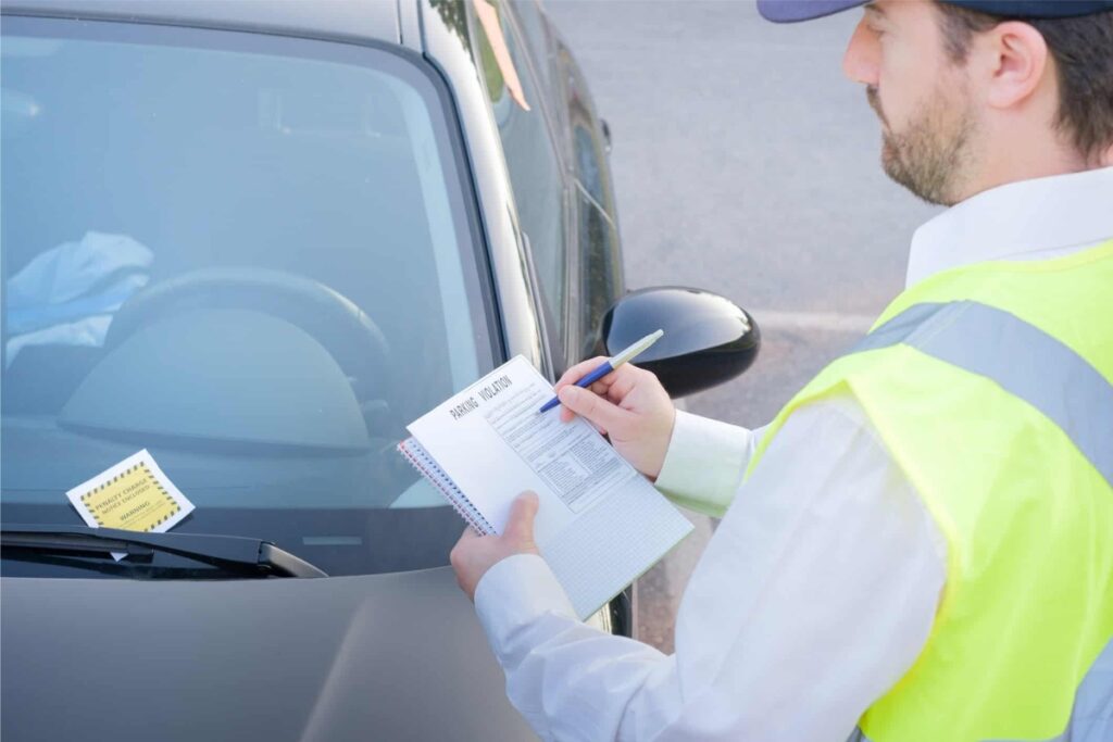 Agente aplicando multa de estacionamento em carro.