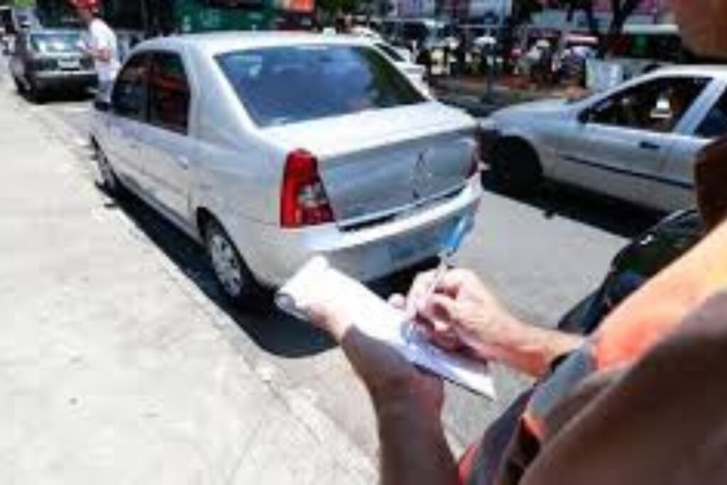 Agente de trânsito multando carro estacionado na rua.