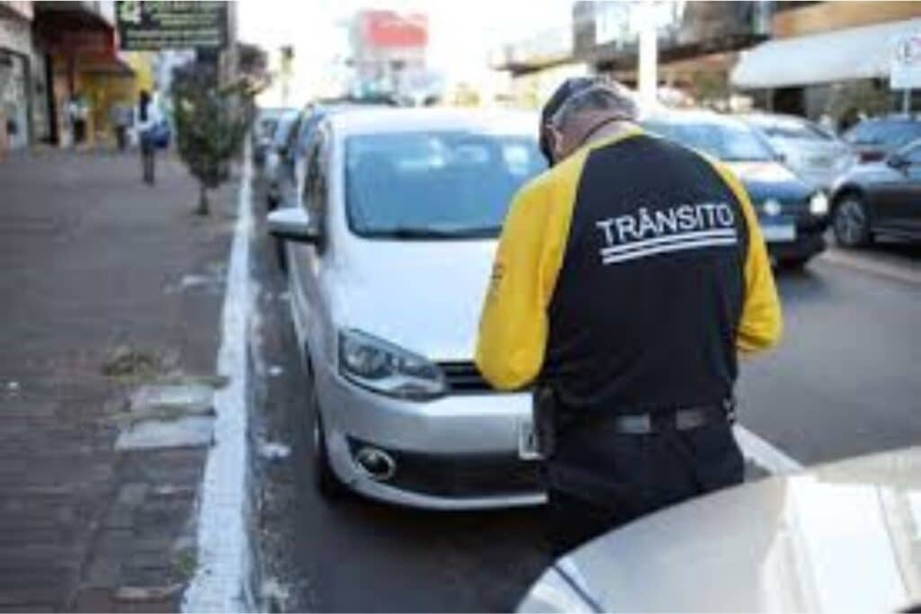 Agente de trânsito fiscalizando carros estacionados na rua.