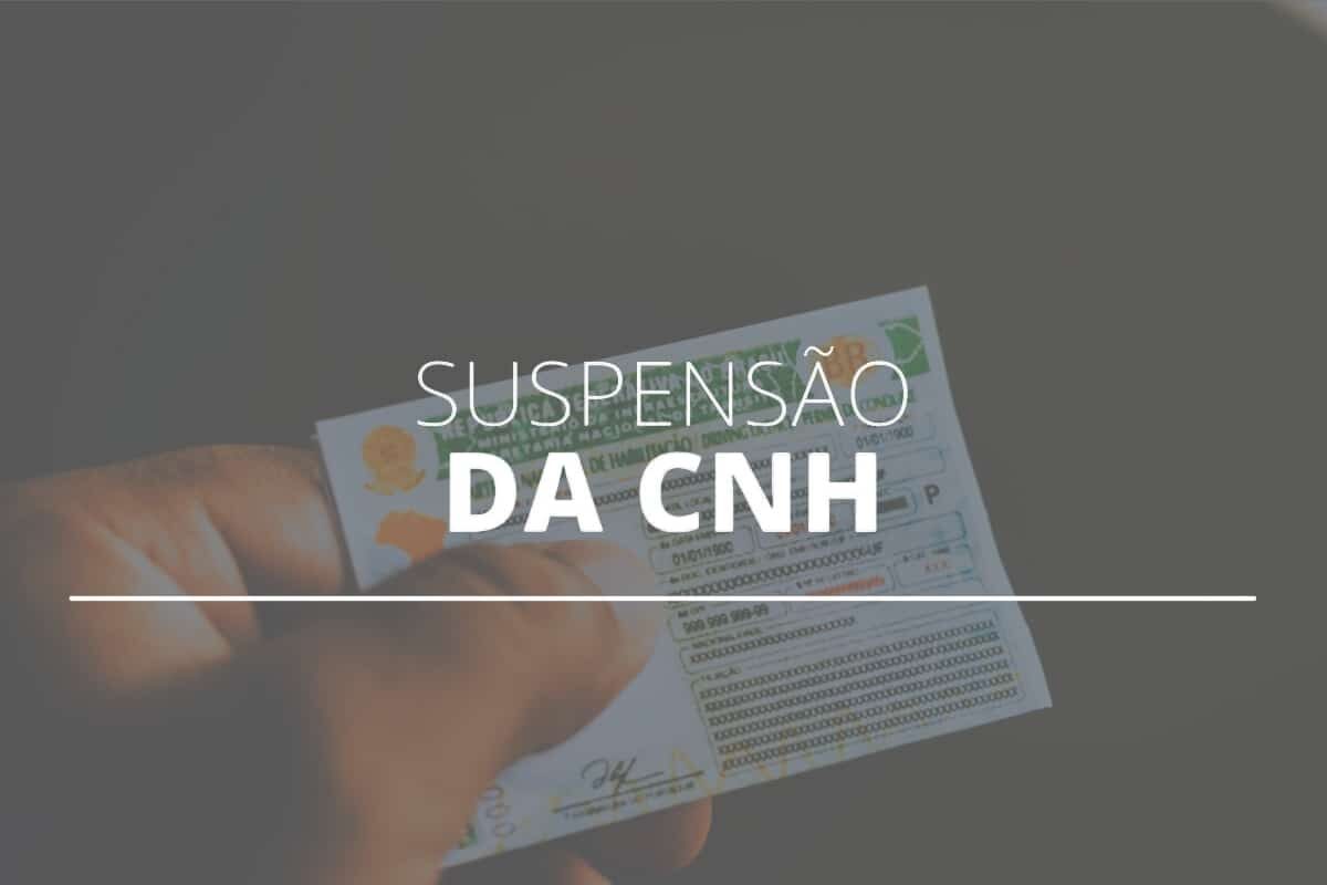 Mão segurando CNH suspensa.