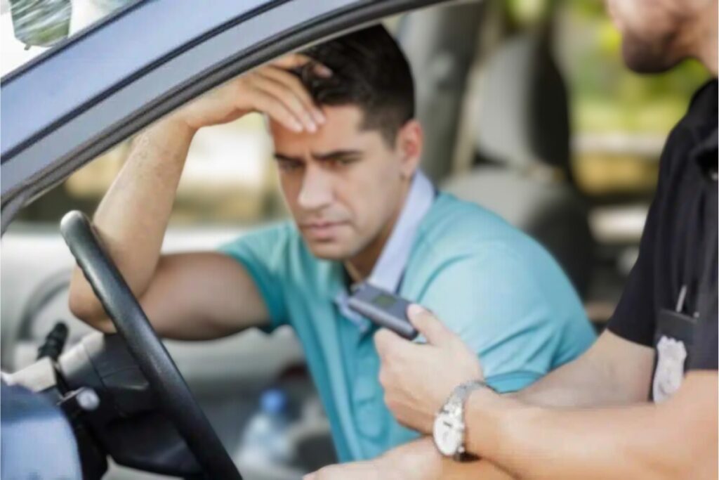 Homem em carro sendo abordado por policial.